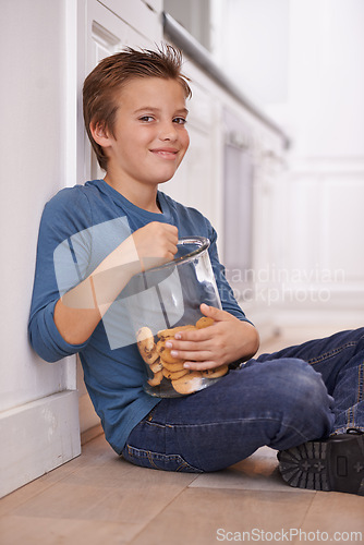 Image of Eating, cookies and portrait of child in home with glass, container or happy with jar of sweets on floor. House, kitchen and kid craving a taste of sugar with biscuit as snack and unhealthy food