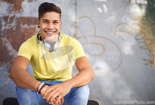 Image of Gen z, portrait and young man at skatepark for skating practice or training for competition. Happy, smile and face of cool male person sitting on ramp with positive, good and confident attitude.