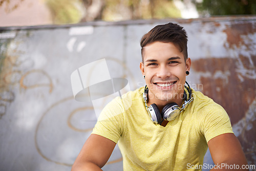 Image of Smile, gen z and portrait of man at skatepark for skating practice or training for competition. Happy, fun and face of cool male person sitting on ramp with positive, good and confident attitude.