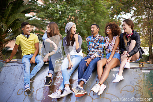 Image of Conversation, happy and group of friends at skatepark in city for bonding, talking and sitting together. Smile, diversity and young teenagers in conversation with skateboard in town for practice.