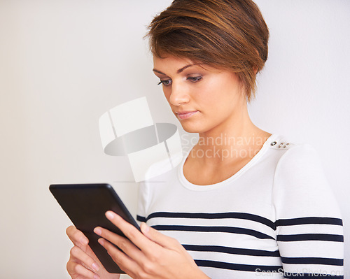 Image of Woman, reading and tablet on a white background for online information, streaming and search by a wall or at home. Young and casual person with digital technology for ebook, internet and social media