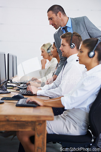 Image of Help desk, manager and phone call with team typing on computer, consultation and customer support. Headset, telemarketing and client service agent at callcenter with training in coworking space