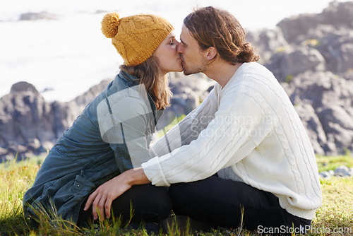 Image of Affection, couple and kissing in nature or outdoor on grass, hilltop and scenery or passionate people. Love, care and romantic date or winter vacation, holiday and relationship together in Sweden