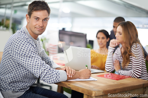 Image of Man, portrait and smile at desk with meeting for business or creative company, planning and teamwork. Male person or designer, office and collaboration for startup agency, paperwork and documents.