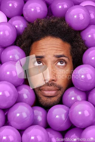 Image of Ball pit, thinking and face of black man with plastic toys for wondering, question and thoughtful on background. Confused, facial expression and person with purple balls, decoration and objects