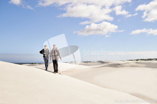 Image of Couple, hiking and sand outdoor or desert with dune, sky and clouds for walking, climbing and move for recreation. Man, woman and young for adventure in weather and dry for season and destination