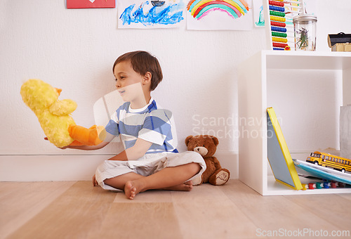 Image of Child, toy and play with teddy, smile and happiness for fun and joy at home or daycare. Boy, cute and positive with stuffed animal, laugh and childcare for growth and cheerful on wood floor in house