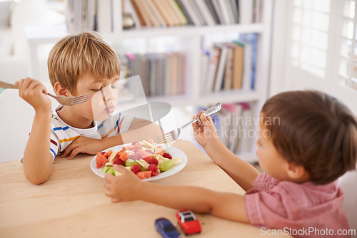 Image of Children, boys and eating fruit salad for lunch in dining room for nutrition, healthy meal and wellness in home. Siblings, kids and breakfast bowl with watermelon, grapes and berries for sharing