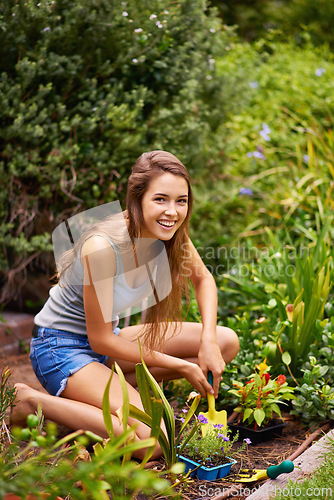 Image of Woman, tool and flowers for gardening and plant in environment outdoor with soil and sunshine. Gardener and smile with spade on grass for sustainability, growth and earth for lawn or garden and eco