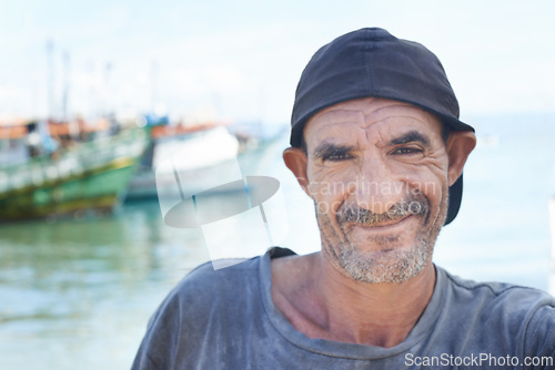 Image of Fisherman, portrait and rugged man with smile, boats and fishing trawler in ocean. Wrinkles, aged and mature happy male from Brazil, close up and self employed with nomadic lifestyle on the water