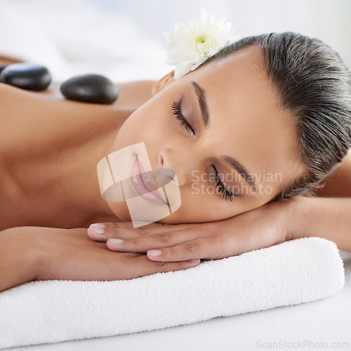 Image of Zen, hot stone and woman with massage at spa for wellness, health and back treatment. Self care, cosmetic and young female person sleeping for warm rock skin therapy at natural beauty salon.