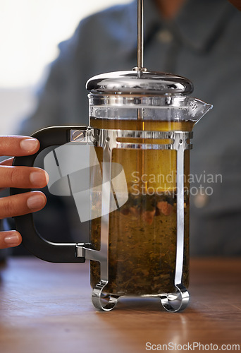 Image of Closeup, person and hands with tea plunger for brewing, heathy and fresh beverage start morning. Cafe, table and prepare for customers on breakfast to taste, drink and enjoy for beautiful day.