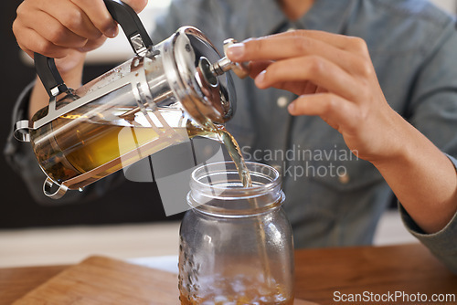 Image of Closeup, person and hands with brewing tea to start morning, cafe and table before work. Plunger, pour, fresh and healthy beverage for customer on breakfast, teapot and drink to enjoy beautiful day