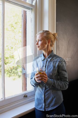 Image of Woman, tea and thinking at window in home for herbal detox or healthy drink with leaves, relax or morning. Female person, glass and thoughts for wellness benefits or apartment, beverage or breakfast
