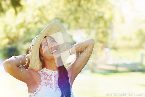 Image of Woman, travel and happy relaxing in park or garden, smiling and joyful on summer holiday. Female person, peace and enjoy vacation in countryside, outdoors and hat on weekend adventure in nature