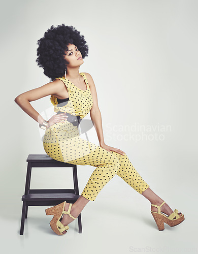 Image of Black woman, portrait and retro in studio, vintage and hand on waist, unique and dots in clothes. Fashion, hippy and person with hair, model and strong African lady, yellow and girl sitting in chair