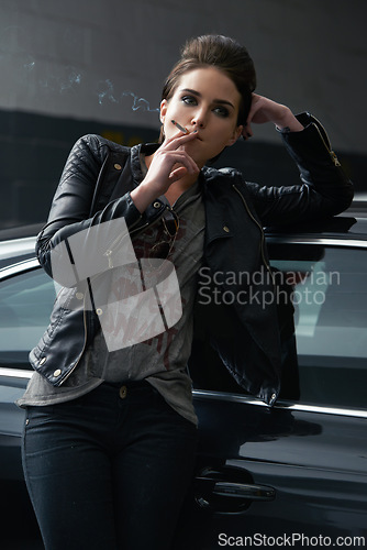 Image of Woman, waiting and smoking cigarette on car in parking lot for pick up or transportation. Female person, smoker or driver in fashion with leather jacket and inhaling tobacco by stationary vehicle