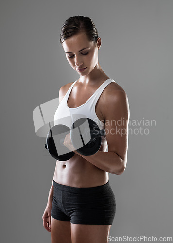 Image of Woman, fitness and weightlifting with dumbbell for muscle gain, workout or exercise on a gray studio background. Active female person or bodybuilder with weight for arm or bicep curl on mockup space