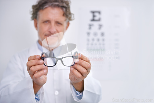 Image of Glasses, eye exam and portrait of optometrist in clinic to check or test vision in healthcare. Mature, doctor and reading letters on wall in medical assessment or consultation for contact lenses