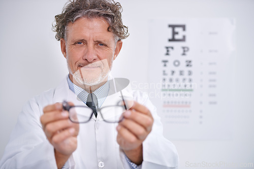 Image of Glasses, test and portrait of optometrist in clinic to check vision and eye exam in healthcare. Mature, doctor and reading letters on wall in medical assessment or consultation for contact lenses