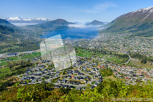 Image of Majestic mountain town overlooking a misty fjord at dawns first 