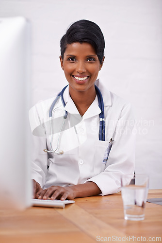 Image of Portrait, doctor and happy woman typing on computer in hospital for healthcare career in India. Face, smile and medical professional on keyboard for wellness and online research at desk in clinic