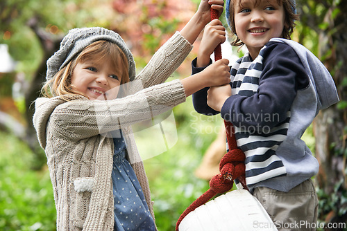 Image of Children, smile and swing in a backyard in winter together with sibling and fun in garden. Youth, nature and excited on tire in fall at home outdoor with kids playing by tree with happy girl and boy