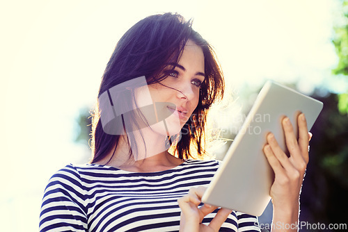 Image of Woman, nature and sunshine with tablet for online communication, reading ebook or social media in park. Female person, low angle and technology with happiness for connectivity, blog or networking