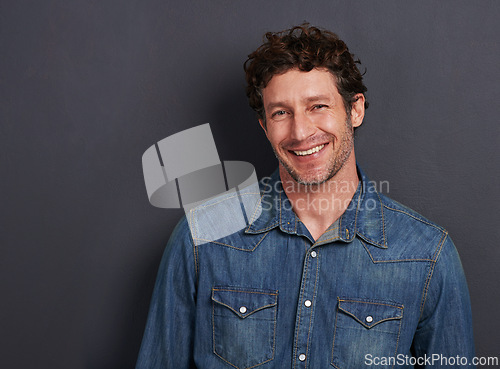 Image of Studio, portrait and man with smile, casual fashion and mockup space for creative professional. Relax, happy and face of person with confidence, pride and trendy denim style on dark grey background