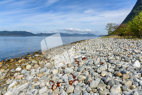 Image of Serene seaside pebble beach on a sunny day with distant mountain