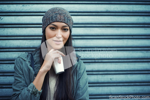 Image of Woman, fashion and coffee with portrait, urban and city street or background for style. Asian student, beanie and jacket in cape town with winter, cold and planning with metal garage door with denim