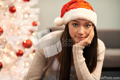 Image of Portrait, bored and Christmas with unhappy woman in living room of home for lonely celebration. Depression, sad or frustrated and young person with Santa hat in apartment for December holiday season