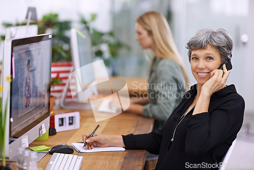 Image of Portrait, phone call and mature manager writing notes, talking or coworking in startup. Face, happy woman and ceo on cellphone with book for info, business and creative designer on computer at desk