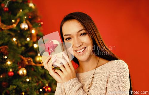 Image of Portrait, smile and Christmas with woman, gift box and package on a red studio background. Face, person and girl with Xmas parcel and present with surprise and guessing with giveaway prize or holiday