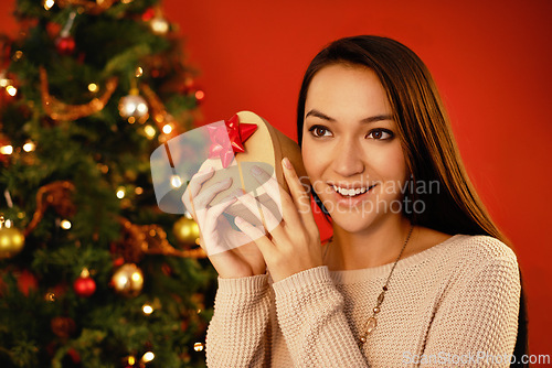 Image of Happy, smile and Christmas with woman, gift box and parcel on a red studio background. Excited, person and girl with Xmas present and package with surprise and guessing with giveaway prize or holiday