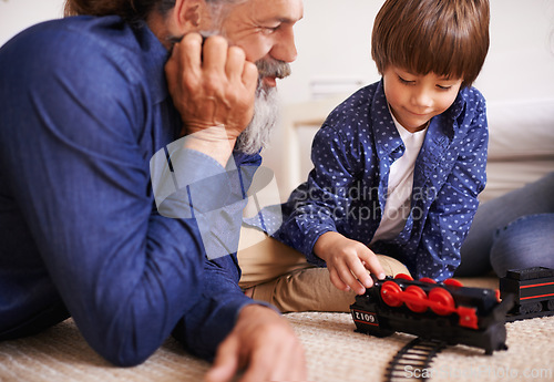 Image of Grandfather, grandson and play with toy, train and fun in home or house with joy. Man, child and happiness with smile, youth and childhood development for future growth and bonding or care together