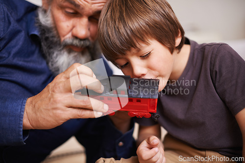 Image of Grandfather, toy and train with boy child, playing and bonding in family home. Grandpa, young kid and childhood development with games and fun, quality time and love with senior retired man