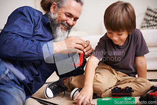 Image of Grandfather, laugh and toy train with boy child, playing and bonding in family lounge. Grandpa, young kid and childhood development with games and fun, quality time and love with elderly retired man