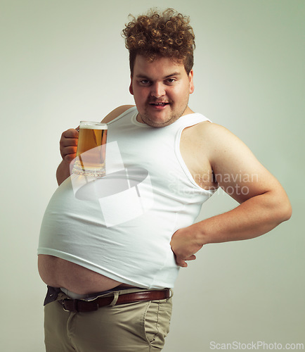 Image of Obese, weight gain and lager for man in studio with drink for unhealthy habit, plus size and joke. Overweight person with glass on fat stomach for balance, drunk and humor for alcohol and comic