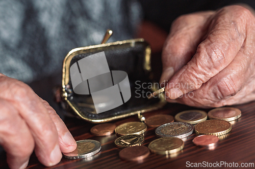 Image of Detailed closeup photo of elderly 96 years old womans hands counting remaining coins from pension in her wallet after paying bills. Unsustainability of social transfers and pension system.