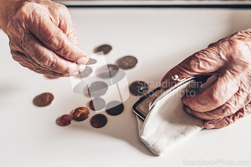 Image of Detailed closeup photo of elderly 96 years old womans hands counting remaining coins from pension in her wallet after paying bills. Unsustainability of social transfers and pension system.