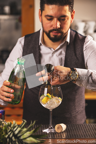 Image of Bartender pouring gin into glass with ice