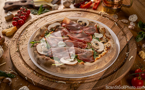 Image of Delicious pizza with prosciutto and mushrooms