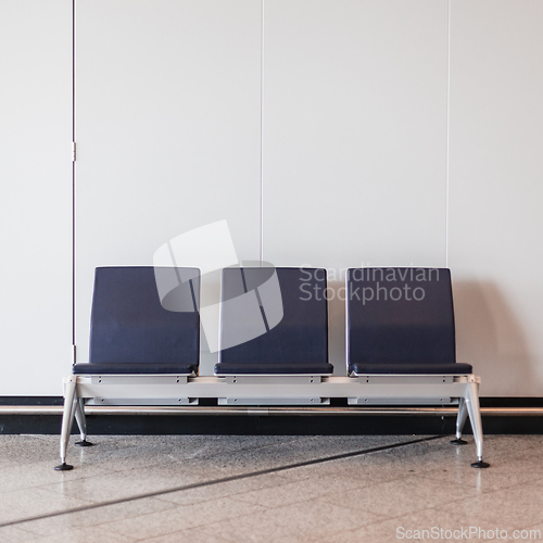Image of Rectangular chairs lined up against white wall in waiting room