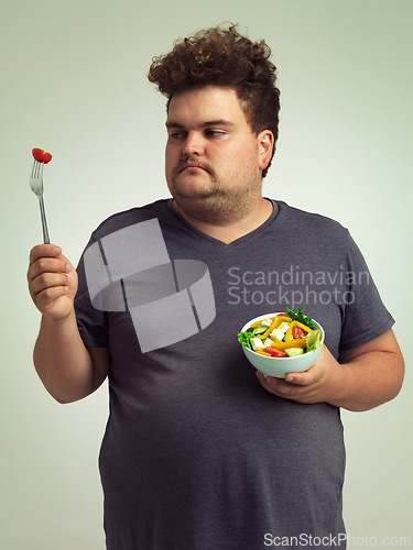 Image of Unhappy, man and salad in studio for weight loss, healthy food and organic nutrition for wellness. Male person, plus size and disgust with meal for vitamin c, detox or lifestyle change for diet