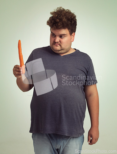 Image of Man, vegetables and carrot in studio with thinking for healthy snack, detox and vitamin c for wellness. Plus size, male person and unhappy with organic food for nutrition, lifestyle and diet