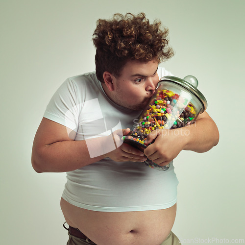 Image of Love, candy and plus size man kissing glass jar in studio on gray background for craving or hunger. Food, obsession or possessive and crazy young person with lots of sugar for unhealthy eating