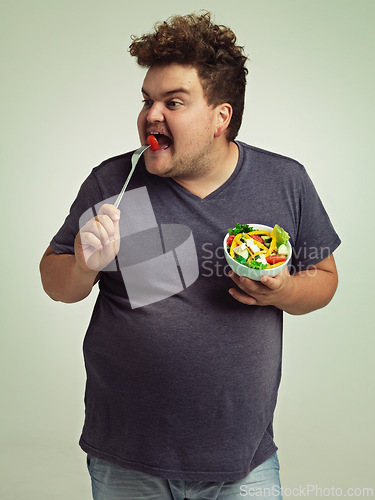 Image of Studio, plus size and man with eating salad for weight loss, healthy diet and vitamin c benefits. Fork, tomato and male person with organic food for detox, nutrition or commitment to lifestyle change