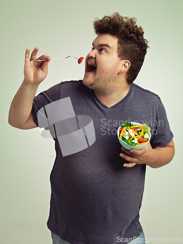 Image of Studio, man and eating salad for weight loss, healthy diet and lifestyle benefits for wellness. Plus size, male person and fork with organic food for nutrition, vitamin c and hungry with lunch meal