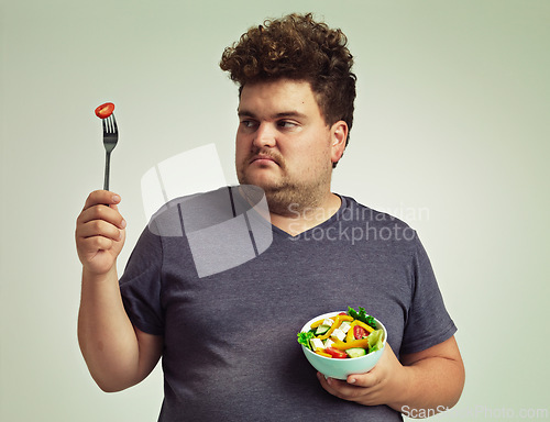 Image of Plus sized, man and unhappy with food for healthy diet, fork or bowl and salad for wellness on studio background. Male person, detox and lose weight for health, eating disorder and nutrition